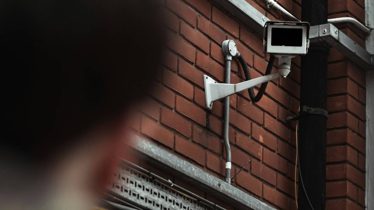 A man looking at a surveillance camera mounted on the wall